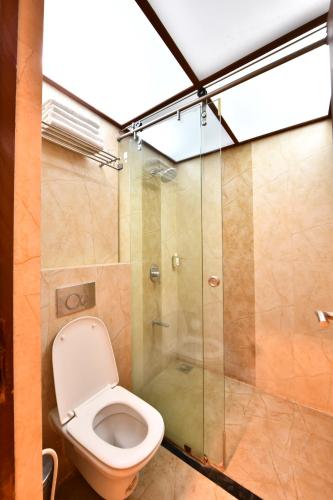 a bathroom with a toilet and a glass shower at Click White House Residency, Vadodara in Vadodara