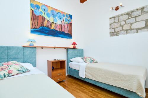 a bedroom with two beds and a painting on the wall at Apartment Ermineous A34 in Dubrovnik
