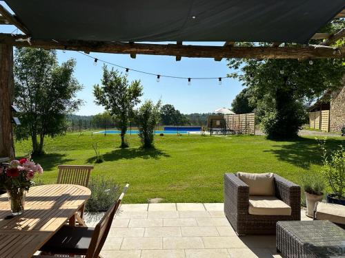 un patio con tavolo e sedie e un campo di Maison d'Amis Des Hirondelles a Lempzours