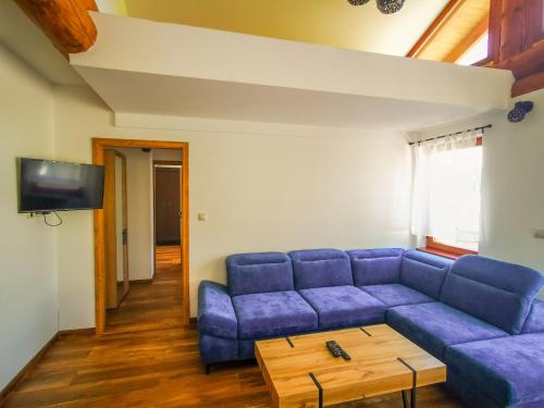 a living room with a blue couch and a table at Koliba Pod Skalami in Súľov-Hradná