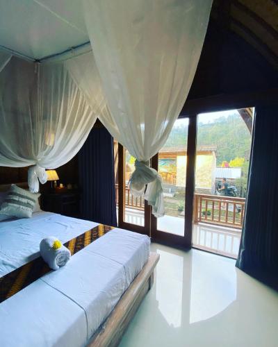 a bedroom with a bed with curtains and a window at Batur cottage in Kubupenlokan