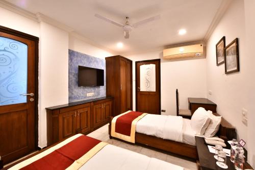 a hotel room with two beds and a television at Click White House Residency, Vadodara in Vadodara