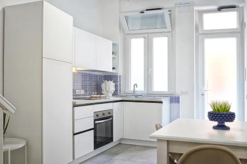 a white kitchen with white cabinets and a table at Lo Scoglio della Formica B&B in Capo dʼOrlando