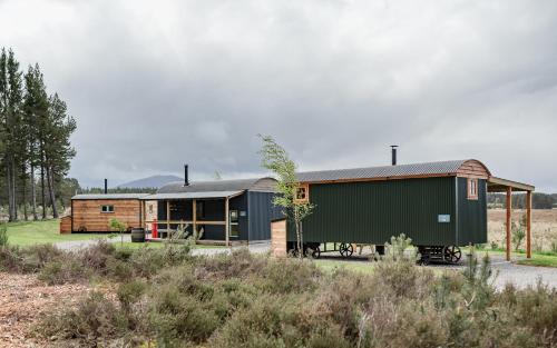 a barn conversion with a train car in front of it at Highland Shepherd Huts in Nethy Bridge