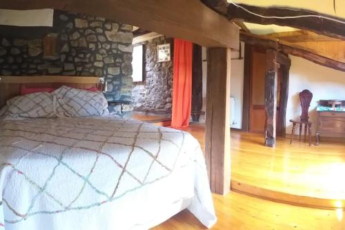 - une chambre avec un lit et un mur en pierre dans l'établissement Descanso en Burgozarre, à Mungia