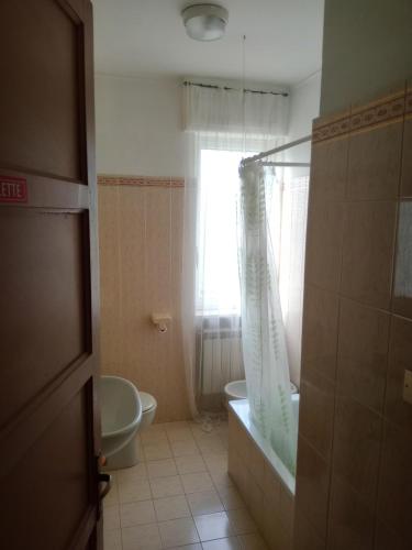 uma casa de banho com uma banheira, um WC e uma janela. em Locanda Ostu di San giacu em Boves