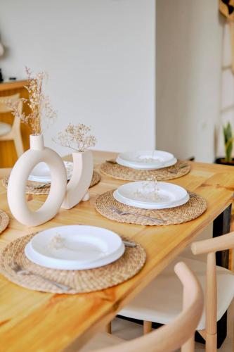 a wooden table with white plates and vases on it at Bali-inspired Villa with Dipping Pool by Pallet Homes in Iloilo City