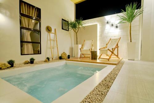 a swimming pool in a house with two chairs at Bali-inspired Villa with Dipping Pool by Pallet Homes in Iloilo City