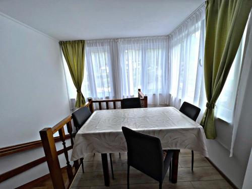 ein Esszimmer mit einem Tisch, Stühlen und Fenstern in der Unterkunft Casa Milla in Sovata
