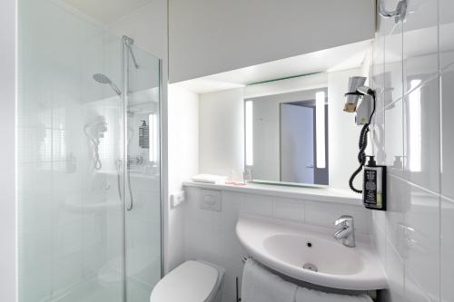 a white bathroom with a toilet and a sink at ibis Nürnberg City am Plärrer in Nuremberg
