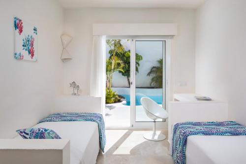 Habitación blanca con 2 camas y balcón. en Bahiazul Resort Fuerteventura, en Corralejo