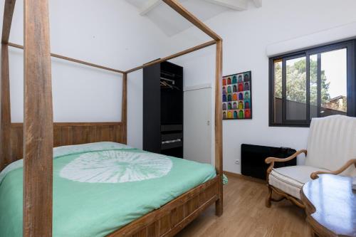 een slaapkamer met een hemelbed en een stoel bij Grand Appartement De Standing in Seignosse