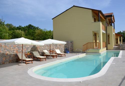 a swimming pool with chairs and umbrellas next to a building at Agriturismo Gradec in Aurisina