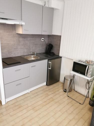 une cuisine avec des armoires blanches, un évier et un micro-ondes dans l'établissement Jolie studio avec la vue sur la mer, à Saint-Cyprien