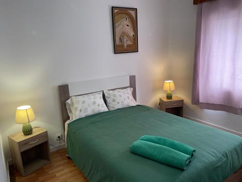 a bedroom with a green bed with two lamps at Espaço perto do aeroporto - Av João Paulo II , número 50 em Ponta Delgada in Ponta Delgada