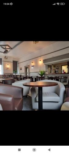 een restaurant met banken, tafels en stoelen bij Tadross Hotel in Barry