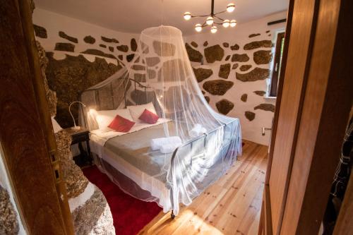 a bedroom with a bed with a mosquito net at Quinta da Lontra in Tábua