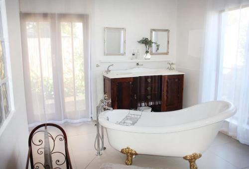 Baño blanco con bañera y lavamanos en Eucalyptus Cottage en Ciudad del Cabo