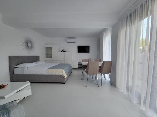 a white bedroom with a bed and a table and chairs at Iliada Studio Oxygen Neptun in Neptun
