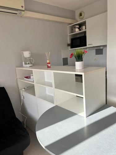 un bureau blanc avec un micro-ondes et des fleurs dans une pièce dans l'établissement Studio residence de tourisme le Fonserane, à Béziers
