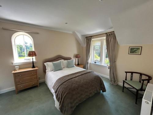 a bedroom with a large bed and two windows at Luxury Garden Cottage in Dalry
