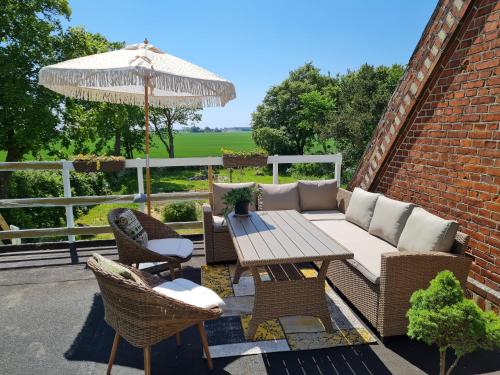 eine Terrasse mit einem Tisch, Stühlen und einem Sonnenschirm in der Unterkunft KirkeLy Bed and Breakfast in Vester Ulslev