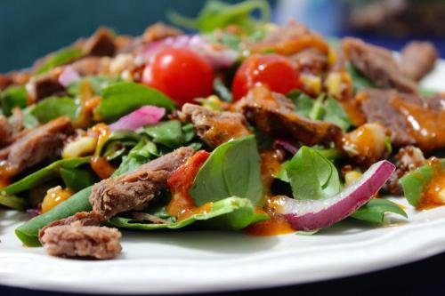 una ensalada con carne y verduras en un plato blanco en Royal en Deventer