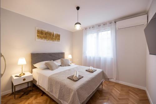 een witte slaapkamer met een bed en een raam bij Bridge Comfort Apartment in Zadar