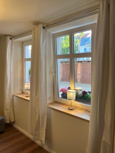 two windows with curtains and a lamp on a window sill at Stadtzentrum, ruhig, praktisch in Greifswald