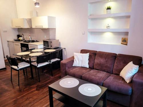 a living room with a couch and tables and a kitchen at Rent-Apart City Center - apartament z 1 sypialnią in Łódź