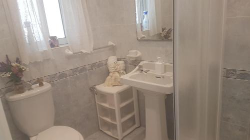 a white bathroom with a toilet and a sink at St Gabriel's in Tarxien