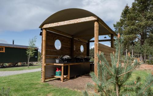 a wooden gazebo with a kitchen in a yard at Highland Shepherd Huts in Nethy Bridge