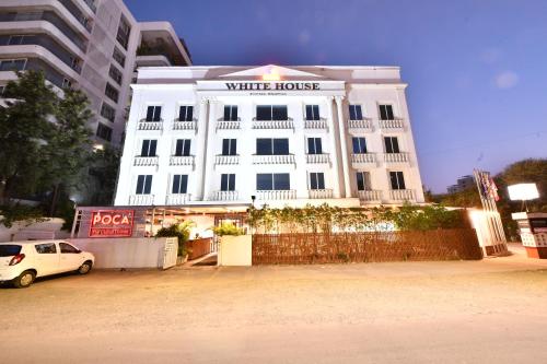 a white building with a white car parked in front of it at Click White House Residency, Vadodara in Vadodara