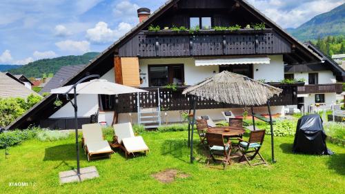 a house with a table and chairs and an umbrella at Snežak (Snowman) in Bohinj