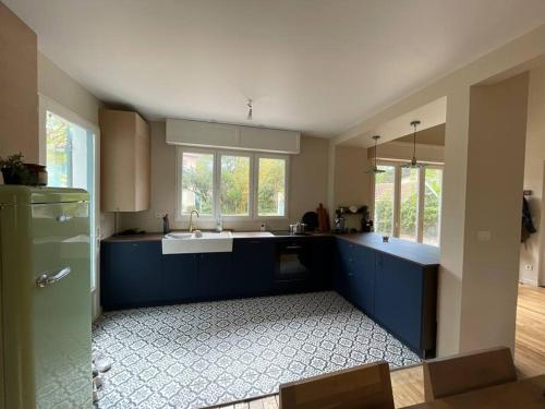 a large kitchen with blue cabinets and a sink at Charmante maison aux Abatilles-piscine-8 pers in Arcachon