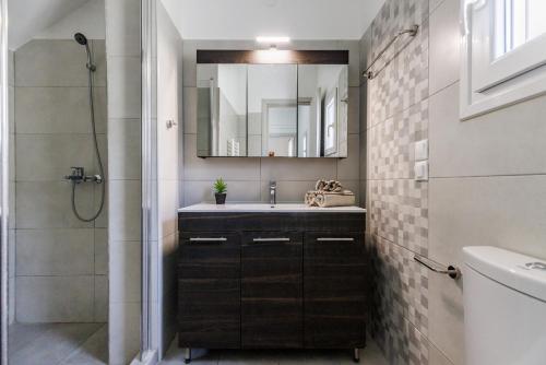 a bathroom with a sink and a mirror and a shower at The Green Yard Apartment in Skopelos Town