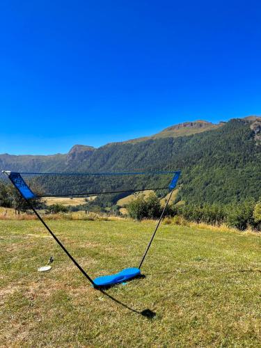 a blue kite in a field with mountains in the background at L'Impradine, grand gîte vue et nature splendides in Le Falgoux