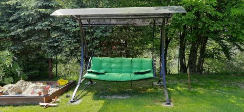 Zielony Domek في تيلسز: كرسي أخضر تحت شرفة في ساحة