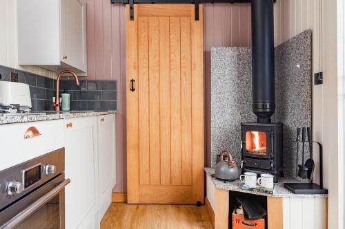 a kitchen with a wood stove on a counter at Highland Shepherd Huts in Nethy Bridge