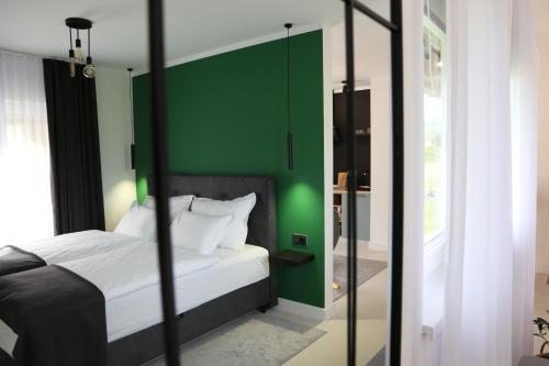 Un dormitorio con una cama con una pared de acento verde en Flora Studio Apartments en Korenica