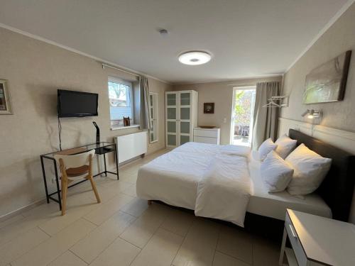 een slaapkamer met een bed, een bureau en een televisie bij Kunsthof Salsitz in Lohme