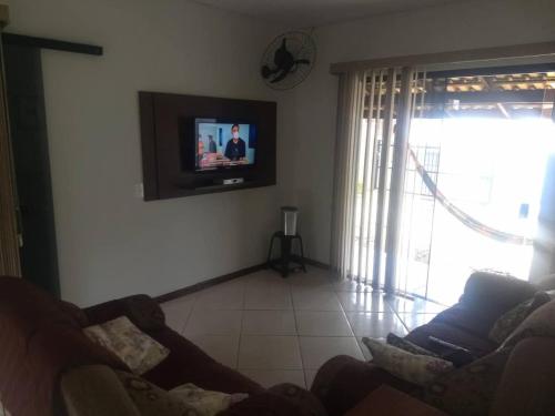 sala de estar con sofá y TV en la pared en Casa Em Penha Sc, en Penha