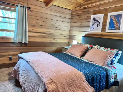 um quarto com paredes de madeira e uma cama com almofadas em Beautiful Cabin on 83 Acres near New River Gorge National Park em Hico