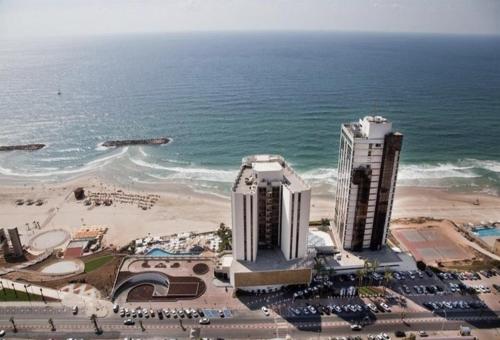 two tall buildings on the beach next to the ocean at Daniel Hotel - Residence Seaside Luxury Flat in Herzelia 
