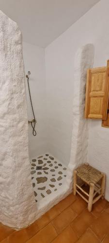a bathroom with a shower with a white wall at Cuevas Los Coloraos - La Cuadra in Villanueva de las Torres