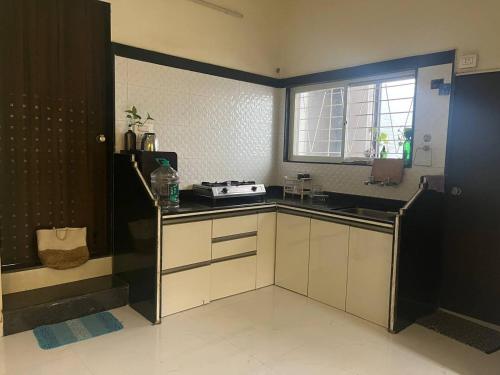 a kitchen with white cabinets and a window at Myra's house in Kolhapur