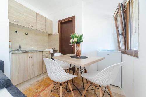 a kitchen with a table with chairs and a vase with flowers at Guest House Zuber in Budva