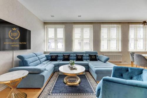 Apartament Faltom Gdynia Centrum في غدينيا: غرفة معيشة مع أرائك زرقاء وطاولة