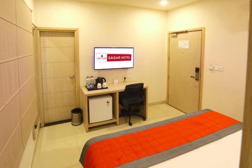 a room with a bed and a desk and a television at Perfectstayz Value Sagar Near Golden Temple in Amritsar