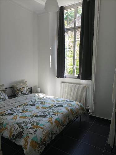 une chambre avec un lit avec une couette colorée et une fenêtre dans l'établissement O'Couvent - Appartement 62 m2 - 2 chambres - A513, à Salins-les-Bains
